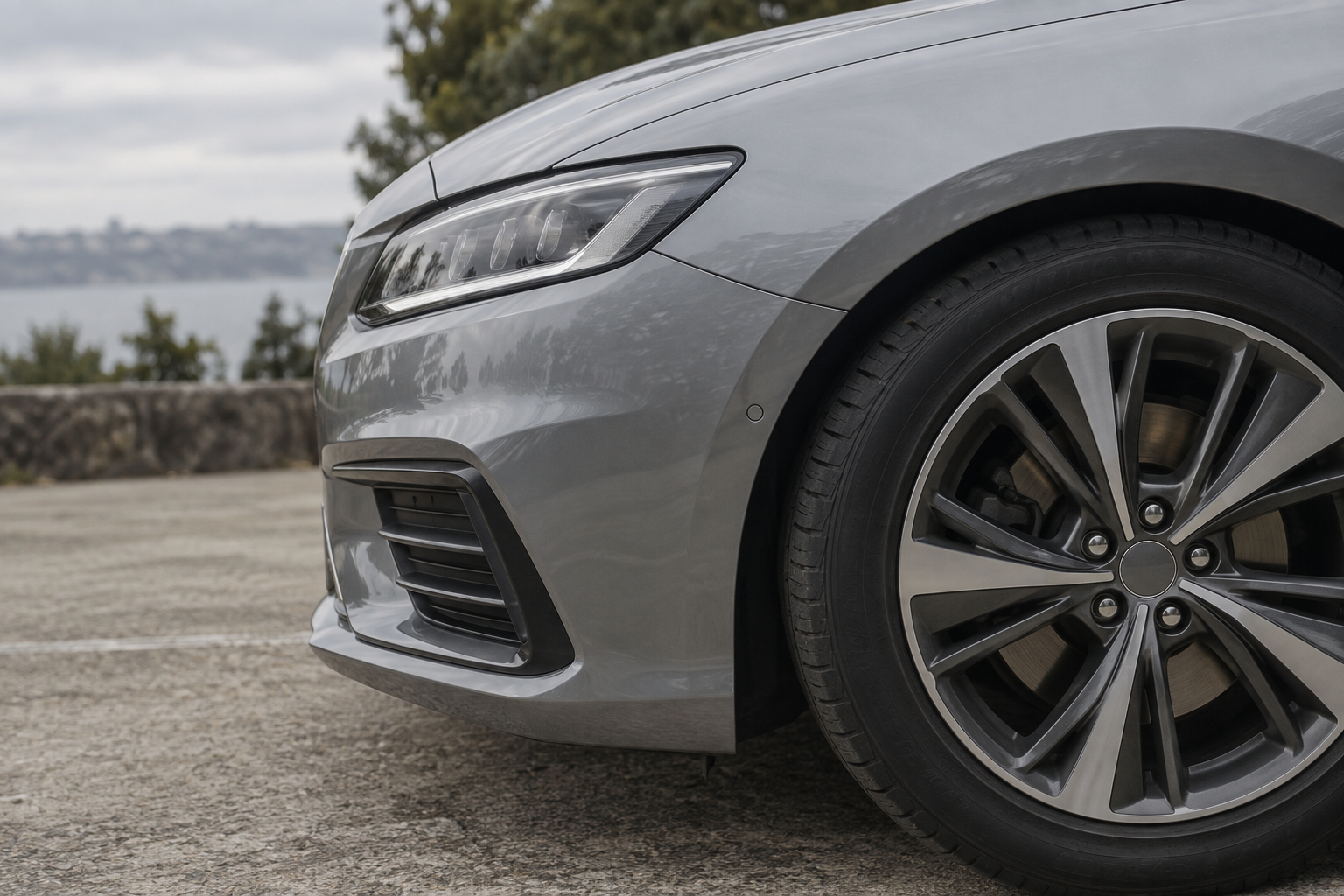 Silver passenger car wheel and front bodywork in soft daylight